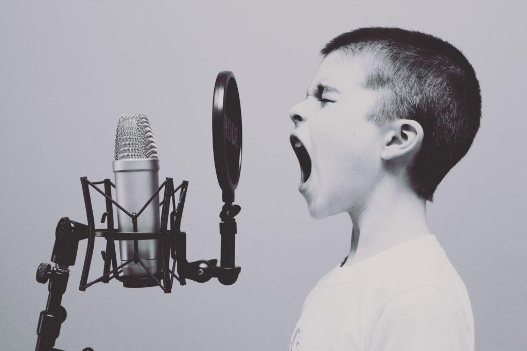 Boy yelling into microphone Photo by Jason Rosewell on Unsplash