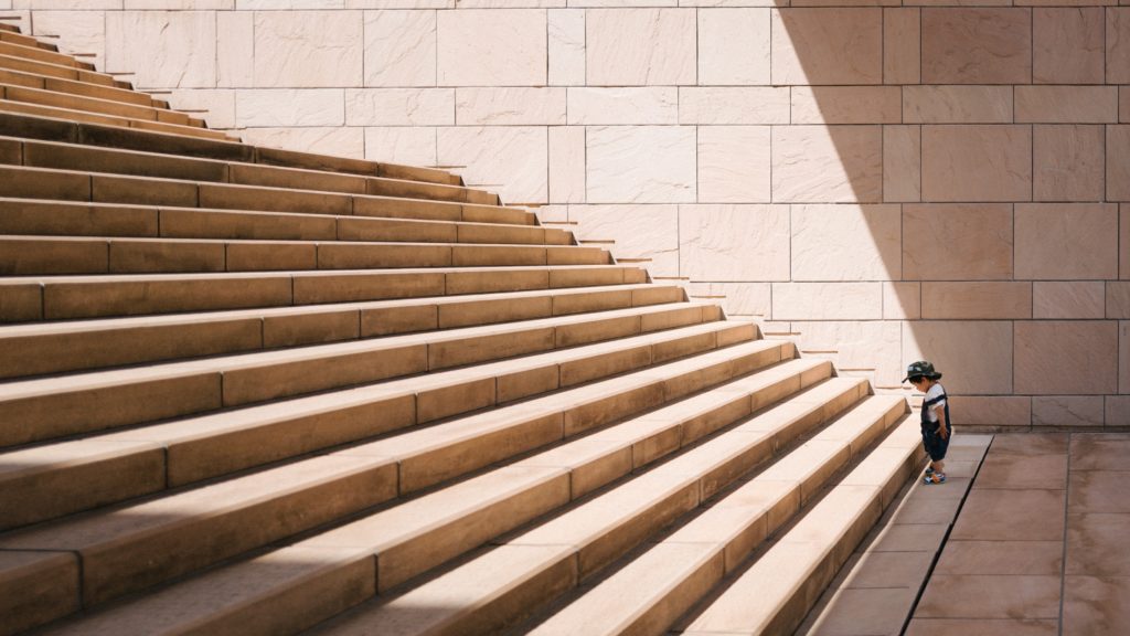Photo of little child at the base of a big staircase by Jukan Tateisi on Unsplash